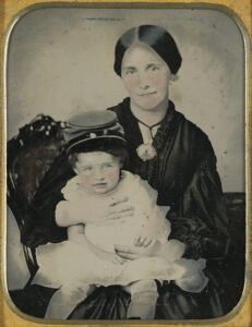 A young Civil War widow holding a child wearing a kepi circa 1861